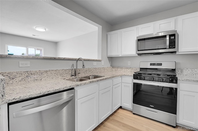 7977 S Kittredge St, Englewood, CO 80112 - kitchen with appliances with stainless steel finishes, white cabinetry, light stone countertops, and light wood-style flooring