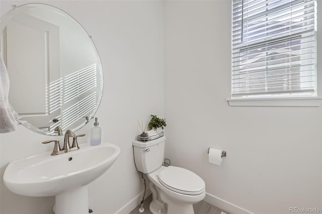 bathroom featuring baseboards, a sink, and toilet