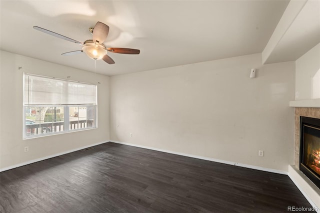 unfurnished living room with ceiling fan, a fireplace, visible vents, dark wood-style flooring, and baseboards