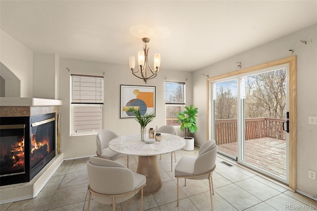 dining space with a tiled fireplace, light tile patterned floors, a notable chandelier, and visible vents