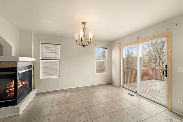 unfurnished dining area with visible vents, a chandelier, tile patterned floors, a tile fireplace, and baseboards