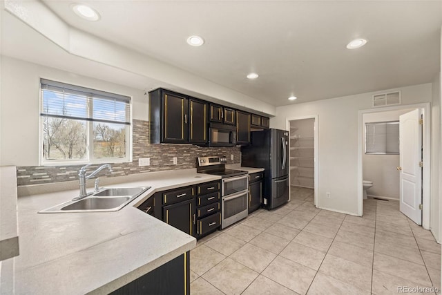 kitchen with visible vents, a sink, light countertops, appliances with stainless steel finishes, and decorative backsplash