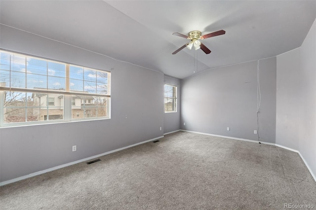 empty room featuring visible vents, baseboards, a ceiling fan, vaulted ceiling, and carpet flooring