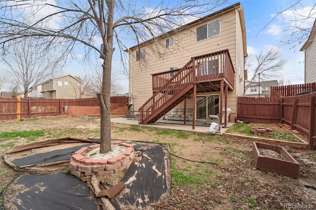 back of property with a fenced backyard, a deck, a patio area, and stairs
