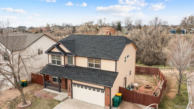 traditional-style house featuring a residential view, a shingled roof, fence, and driveway
