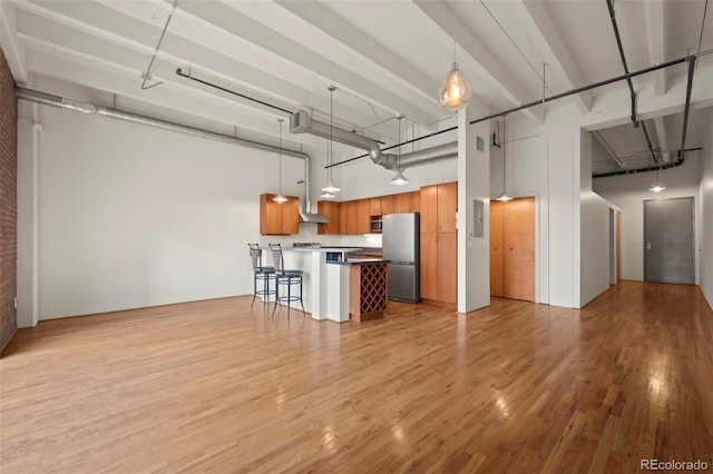 interior space featuring a towering ceiling, electric panel, and light hardwood / wood-style floors