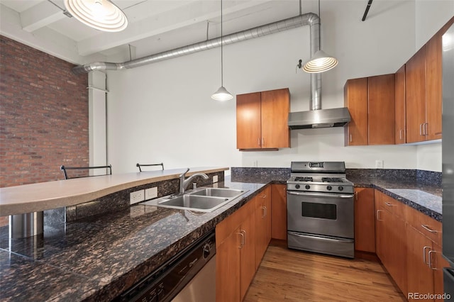 kitchen with pendant lighting, sink, hardwood / wood-style floors, stainless steel appliances, and a high ceiling