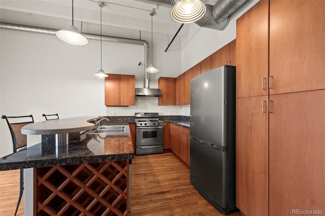 kitchen featuring a breakfast bar, hardwood / wood-style floors, decorative light fixtures, a high ceiling, and stainless steel appliances