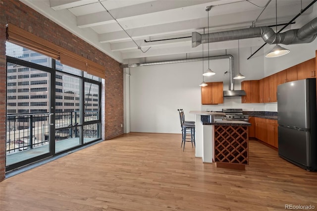 1800 Lawrence St Unit 408, Denver, CO 80202 - kitchen featuring freestanding refrigerator, gas range oven, brick wall, light wood finished floors, and dark countertops