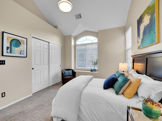 bedroom with a closet, vaulted ceiling, and light carpet