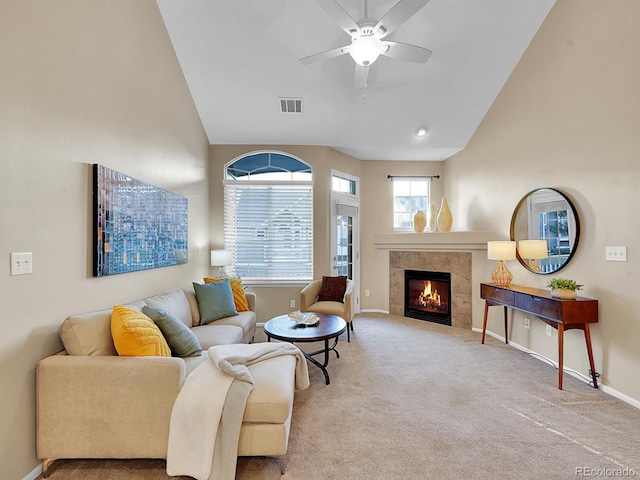 living room with ceiling fan, light colored carpet, lofted ceiling, and a tiled fireplace