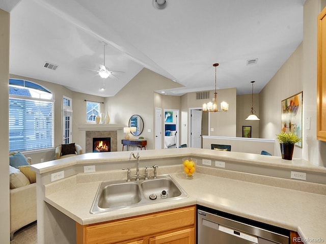 kitchen with lofted ceiling, sink, stainless steel dishwasher, a tile fireplace, and ceiling fan with notable chandelier