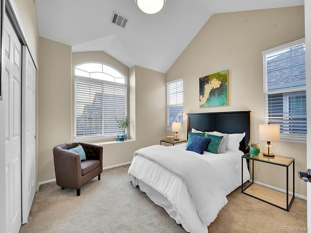 bedroom featuring light colored carpet, vaulted ceiling, and a closet