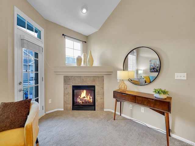 sitting room with a tiled fireplace, vaulted ceiling, and carpet