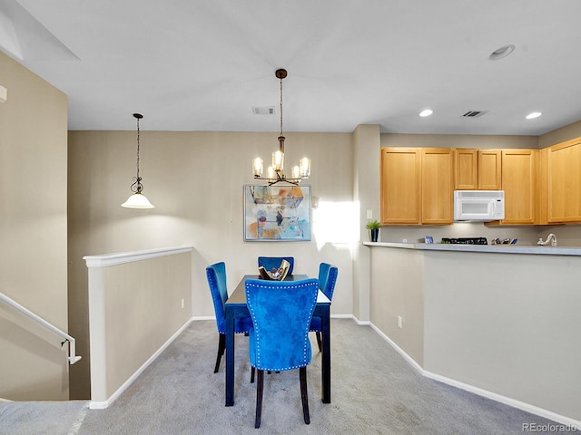 dining room with light carpet and a chandelier