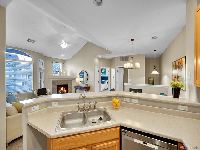 kitchen with sink, dishwasher, a tiled fireplace, ceiling fan with notable chandelier, and vaulted ceiling