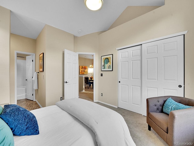 carpeted bedroom featuring vaulted ceiling, ensuite bathroom, and a closet