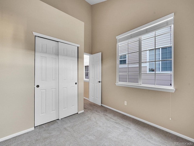 unfurnished bedroom with light carpet and a closet