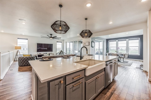 kitchen featuring ceiling fan, a kitchen island with sink, sink, hardwood / wood-style floors, and hanging light fixtures