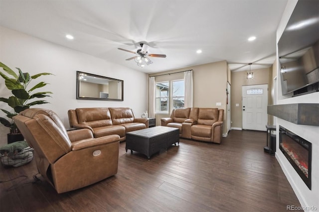 living area with baseboards, dark wood-type flooring, recessed lighting, a ceiling fan, and a glass covered fireplace