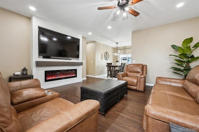 living room featuring baseboards, recessed lighting, a glass covered fireplace, and dark wood finished floors