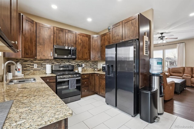 kitchen with a sink, light stone counters, backsplash, and stainless steel appliances