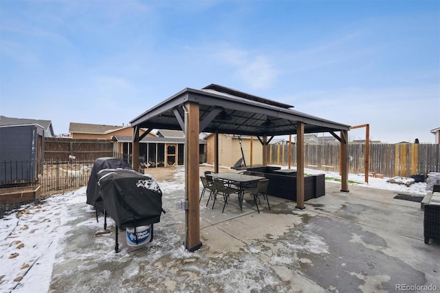 snow covered patio featuring outdoor dining space, a gazebo, area for grilling, and a fenced backyard