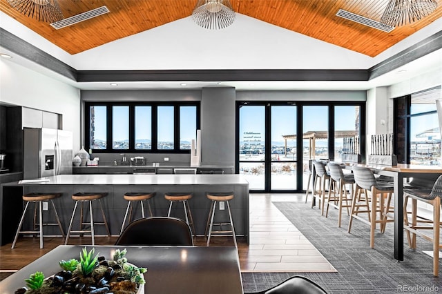 kitchen with stainless steel fridge with ice dispenser, sink, a kitchen breakfast bar, and wood ceiling