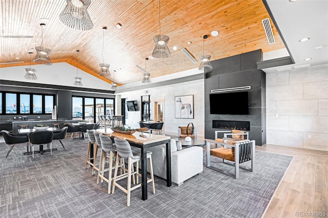 living room featuring wood-type flooring, wooden ceiling, high vaulted ceiling, and a tiled fireplace