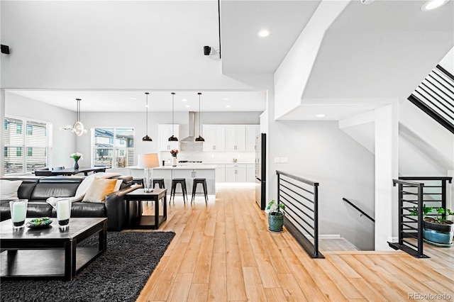 living room featuring a notable chandelier, light wood-type flooring, and vaulted ceiling