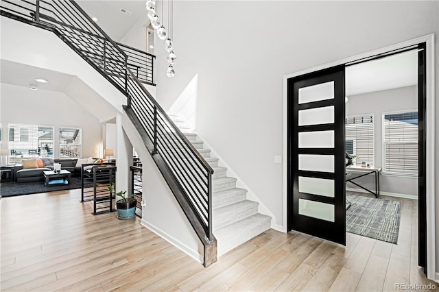 entryway featuring a towering ceiling and light hardwood / wood-style flooring