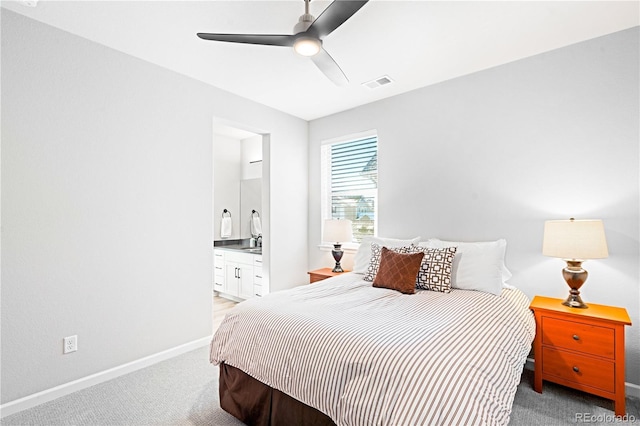 carpeted bedroom with ensuite bath and ceiling fan