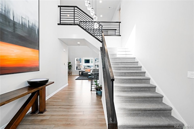 stairs with a towering ceiling and hardwood / wood-style flooring