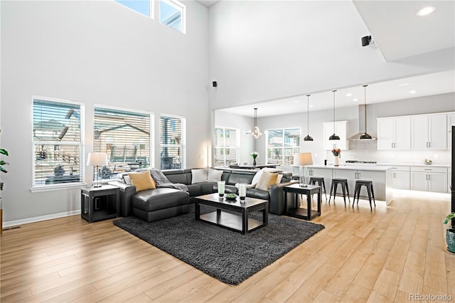 living room with a high ceiling, light hardwood / wood-style flooring, and a notable chandelier