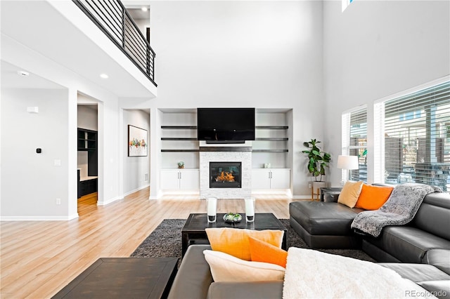 living room featuring a wealth of natural light, light hardwood / wood-style floors, a high ceiling, and built in shelves