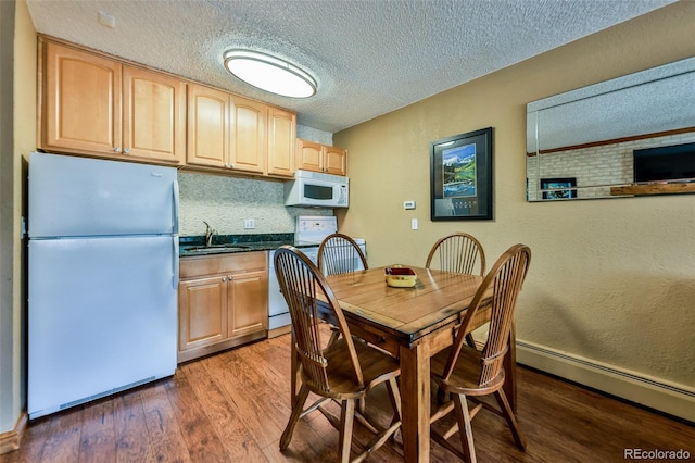 dining space featuring sink, dark hardwood / wood-style floors, a textured ceiling, and a baseboard heating unit