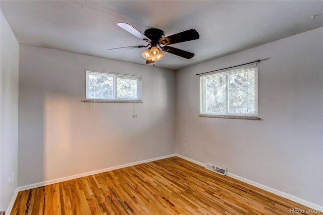 empty room featuring wood finished floors, baseboards, and ceiling fan