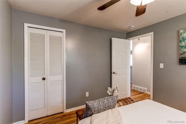 bedroom featuring a closet, wood finished floors, a ceiling fan, and baseboards