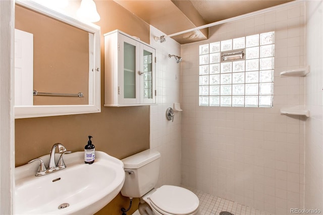 bathroom with a sink, a tile shower, and toilet