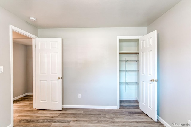 unfurnished bedroom with light wood-style floors, baseboards, and a closet