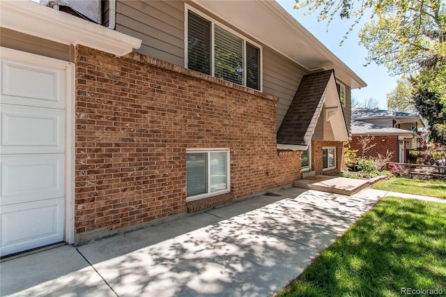 view of side of property featuring brick siding and a patio area