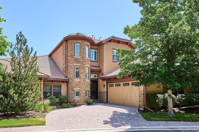 7834 Vallagio Ln, Englewood, CO 80112 - mediterranean / spanish home featuring a tile roof, stone siding, decorative driveway, and stucco siding
