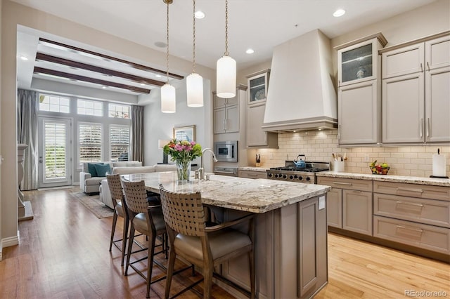 7834 Vallagio Ln, Englewood, CO 80112 - kitchen with custom exhaust hood, tasteful backsplash, stainless steel appliances, a kitchen breakfast bar, and an island with sink