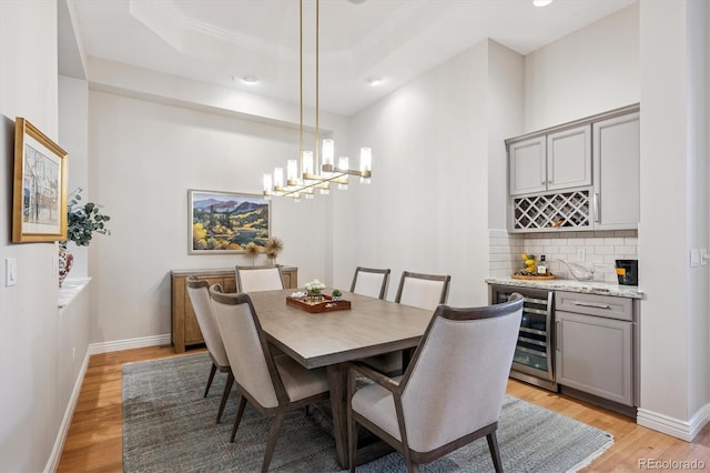 7834 Vallagio Ln, Englewood, CO 80112 - dining space with beverage cooler, light wood-style flooring, a bar, a tray ceiling, and recessed lighting