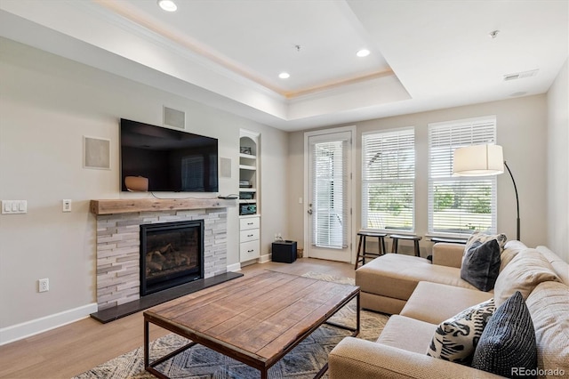 7834 Vallagio Ln, Englewood, CO 80112 - living room with a stone fireplace, light wood finished floors, a raised ceiling, crown molding, and built in shelves