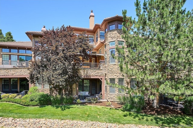 7834 Vallagio Ln, Englewood, CO 80112 - back of property featuring stone siding, a balcony, and a chimney