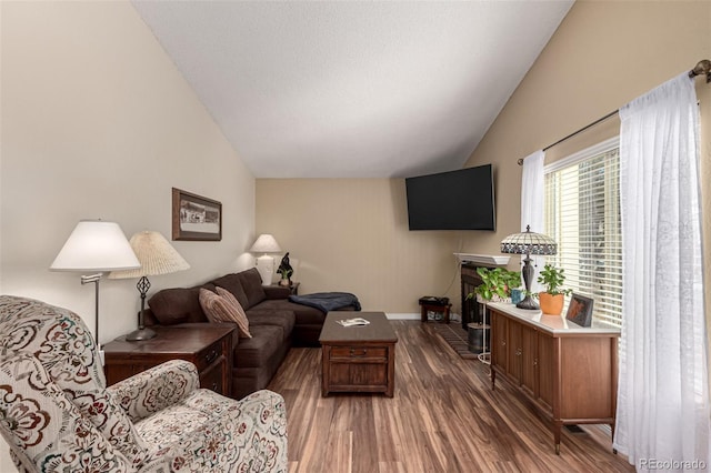 living room with baseboards, wood finished floors, and vaulted ceiling