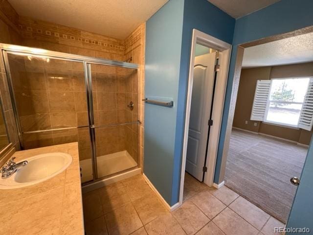 bathroom with tile patterned flooring, vanity, a textured ceiling, and a shower with shower door