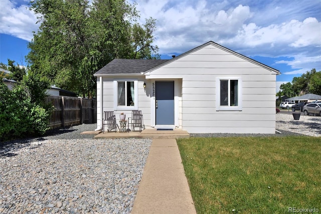 bungalow-style house with a shingled roof, fence, and a front yard