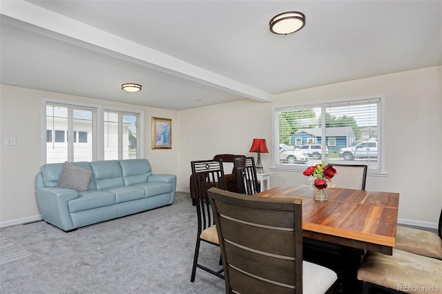 dining area featuring baseboards, beamed ceiling, and light colored carpet